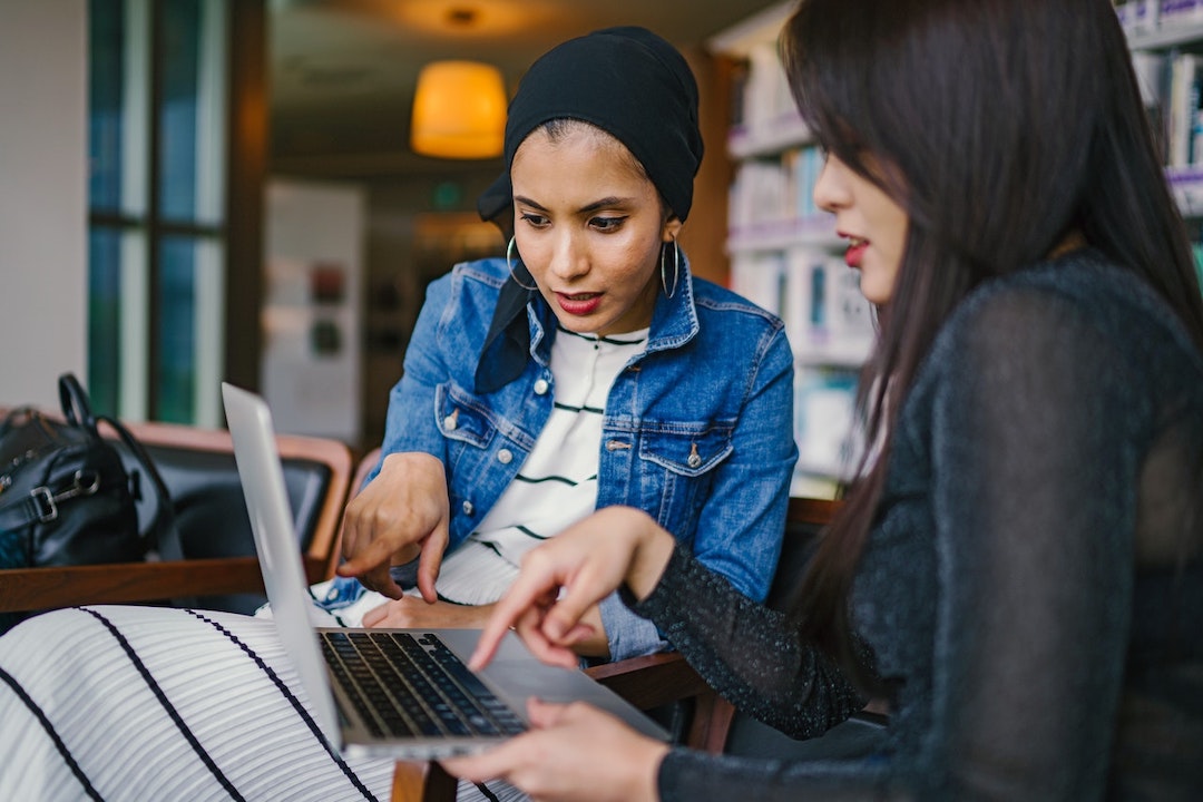 two women discussing laptop